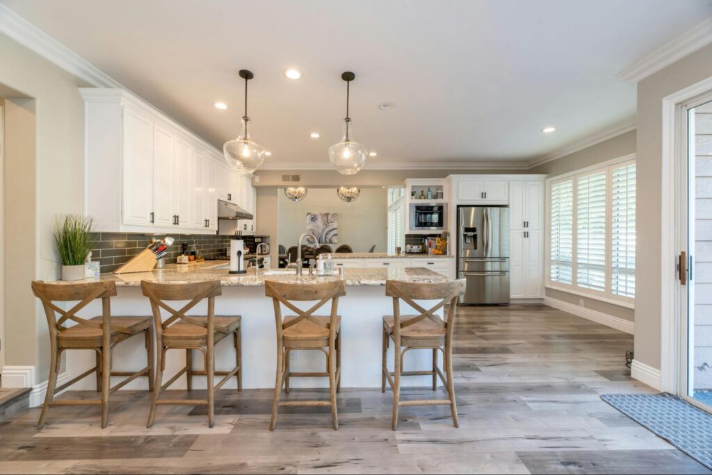 Four barn wooden bar chairs next to an open kitchen