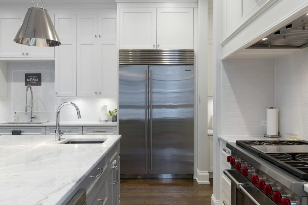 A stainless steel refrigerator beside a white kitchen cabinet